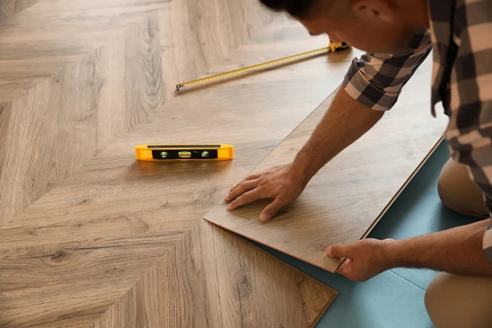 Ouvrier professionnel installant un nouveau parquet à l'intérieur, gros plan