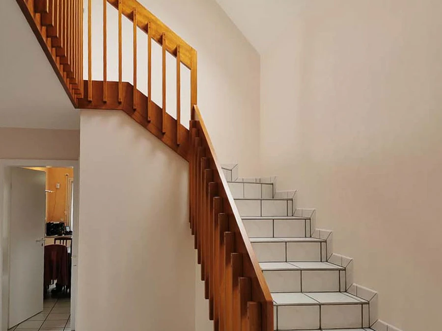Escalier intérieur résidentiel avec rampe en bois naturel et balustres verticaux
