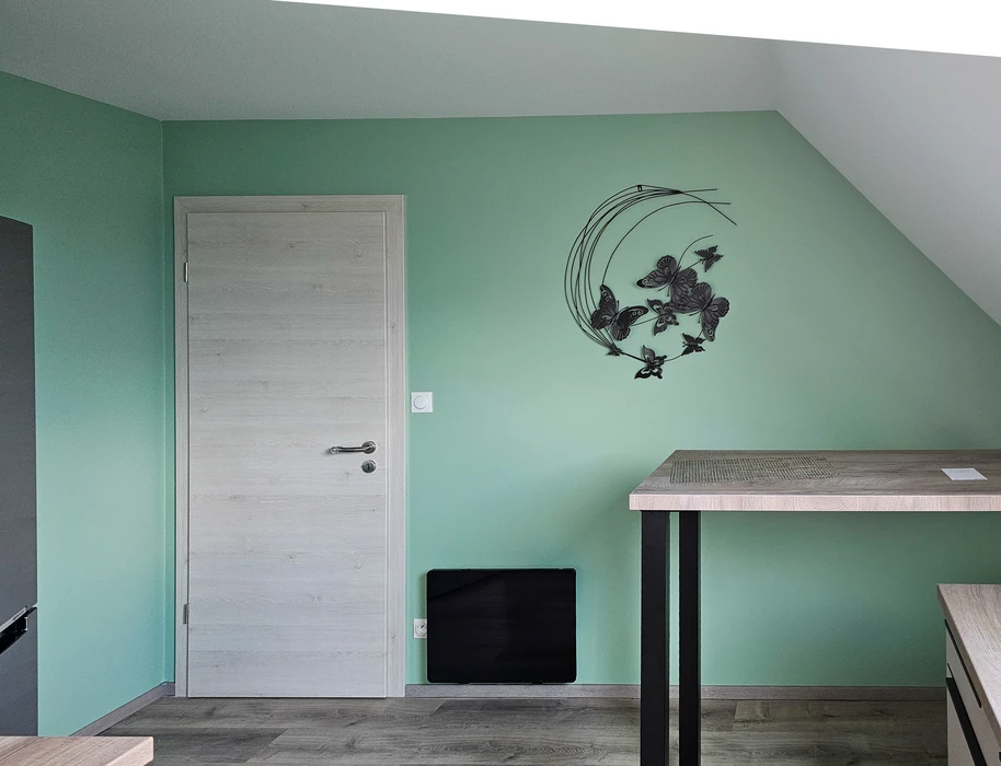 Chambre moderne sous combles avec mur peint en vert menthe, décoration murale métallique représentant papillons dans cercles concentriques