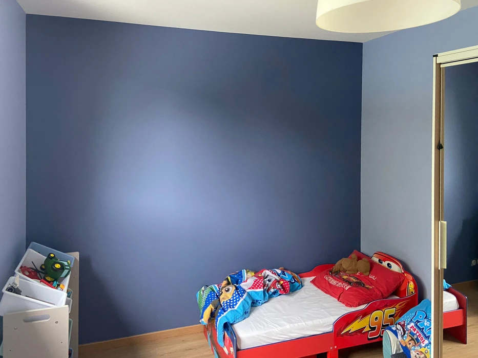 Chambre d'enfant avec mur bleu foncé partiellement peint, transition visible vers bleu plus clair