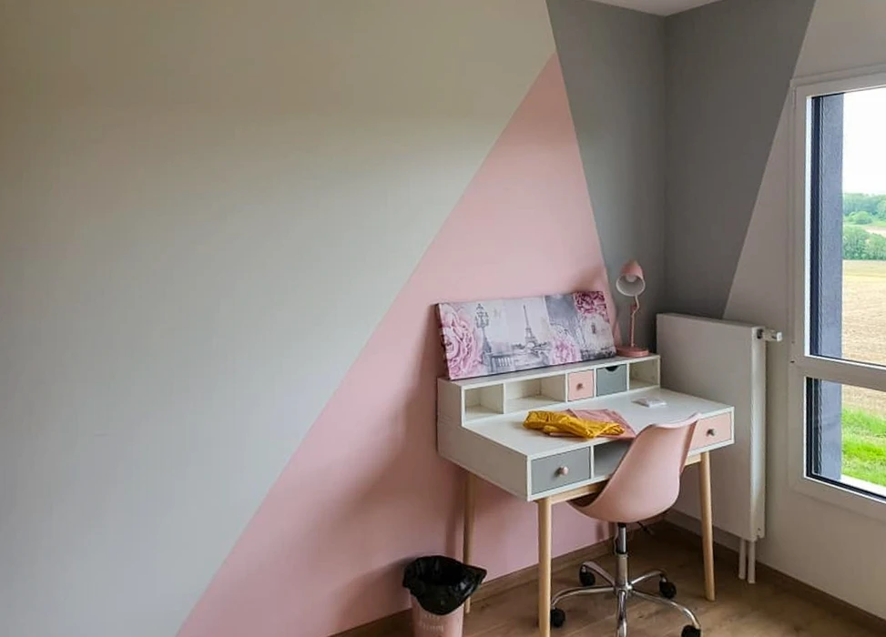 Chambre d'enfant avec mur peint en triangle géométrique rose et gris