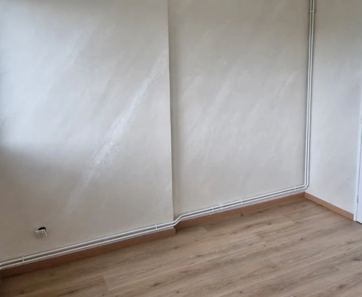 Intérieur d'une pièce vide avec murs blancs présentant traces d'humidité et taches brunâtres