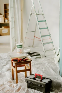 Professionnel peintre homme, se tient dans un appartement armé d'une brosse à rouleaux et seau lors d'une rénovation