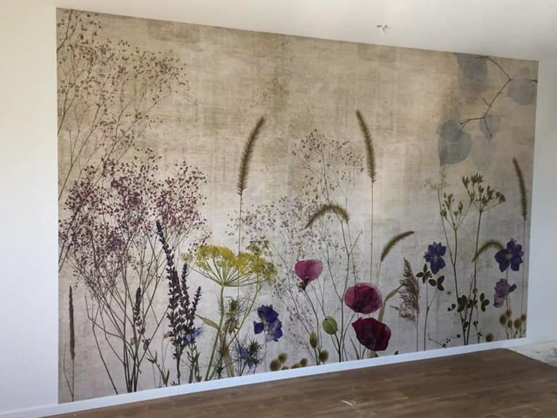 Mur peint d'un salon moderne présentant une fresque architecturale stylisée aux tons rose, blanc et terre cuite
