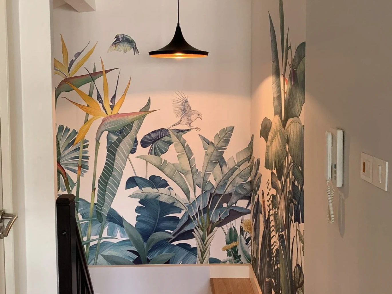 Mur peint d'un salon moderne présentant une fresque architecturale stylisée aux tons rose, blanc et terre cuite