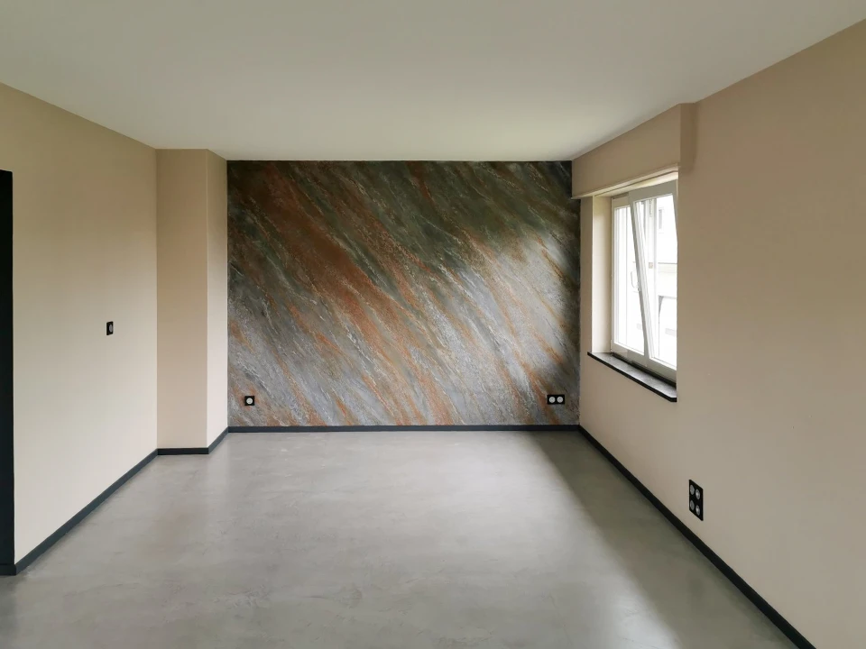 Un constructeur est debout dans une maison dans un processus de rénovation et de mélange de plâtre pour rénover et peindre les murs de revêtement